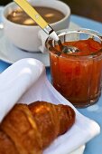 Aprikosenmarmelade mit Croissant und Milchkaffee