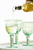 White Wine Pouring from Bottle into Glass; White Background 