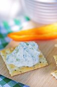 A cracker with a cream cheese and rocket spread