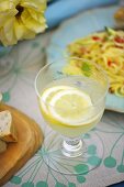Lemonade in a glass next to a pasta dish