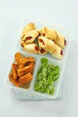 Tomato pastries, chicken fingrers and watercress in a plastic box