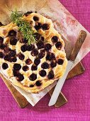Sweet grape flatbread with rosemary on a wooden board
