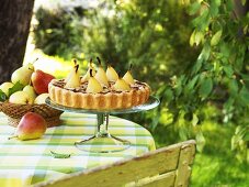 Tarte mit pochierten, ganzen Birnen auf Etagere im Freien