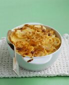 Eine Schüssel Kartoffelgratin mit einem Löffel