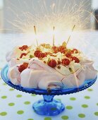 Pink pavlova with raspberries, cream and sparklers