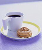 A cup of coffee with a walnut biscuit