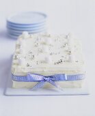 White coconut cake with silver dragées and ribbon