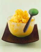 Mangosorbet in einer Glasschüssel mit Löffel