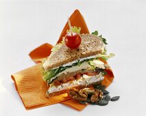 Vollkornsandwich mit Kräuterquark, Salat, Käse und Nüssen