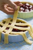 Lattice pastry being placed on a cherry tart