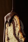 Melted chocolate running over a piece of marble cake