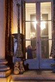 Mädchen steht an der Fenstertür eines weihnachtlich geschmückten Hauses