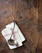 Ladle and tea towel on wooden background