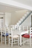 Ein weisser Landhausesstisch vor einer modern-minimalistischen Treppe