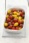 Various types of cherry tomatoes with garlic, thyme and seasalt in a baking dish