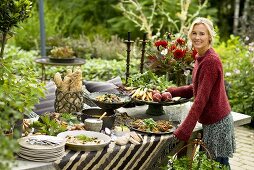 Blonde Frau steht am herbstlichen Buffet