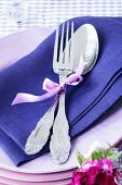 A spoon and a fork on purple napkin