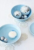 Blue bowls with floating candles and Christmas baubles