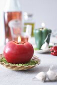 A tomato-shaped candle on a scallop shell dish as table decoration