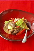 Pieces of beef in pepper sauce with cabbage and red peppers