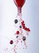 Wild berry juice and berries pouring out of bottle