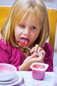 Little girl eating fruit yoghurt
