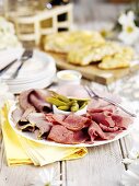 Plate of cold cuts (ham, pastrami) and gherkins