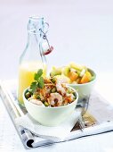 Prawn & noodle salad, fruit salad & orange juice on newspaper