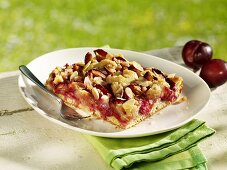 Piece of plum cake with flaked almonds on plate