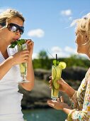 Two women with refreshing cucumber drinks (out of doors)