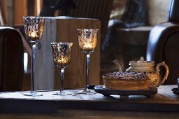 Cake, tea & tealights in glasses on table in country home