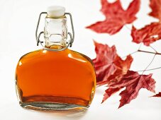 A bottle of maple syrup and red maple leaves