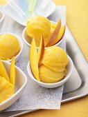 Mehrere Portionen Mango-Eiscreme auf einem Tablett