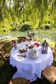 Laid table by pond in romantic garden