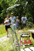 Young people carrying plates and drinks to barbecue area