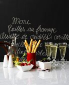 Appetisers & sparkling wine on marble slab in front of slate menu board