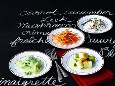 Vier verschiedene Salate auf beschrifteter Schiefertafel