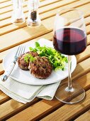 Gegrillte Frikadellen mit Feldsalat, Glas Rotwein