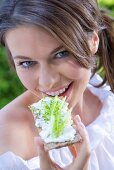 Young woman eating crispbread with cottage cheese & cucumber