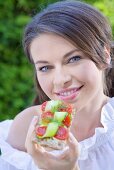 Junge Frau isst Knäckebrot mit Tomaten und Gurken