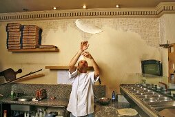 Italian pizza baker throwing dough into the air