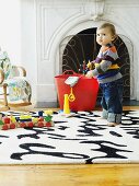 Toddler with toys on rug in front of fireplace