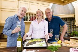 Freunde mit Fisch und Weißwein in der Küche