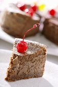 A piece of chocolate cheesecake with a candied cherry