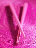 Pink chopsticks on pink background
