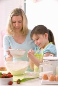 Mother and daughter sieving flour into a bowl