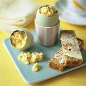 Scrambled egg in eggshell with buttered toast soldiers