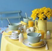 Frühstückstisch mit gekochten Eiern, Orangensaft & Narzissen