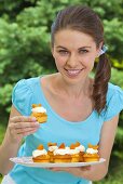 A young woman holding a tray of apricot muffins