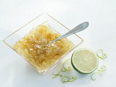 A bowl of lime marmalade with half a lime and zest on the side